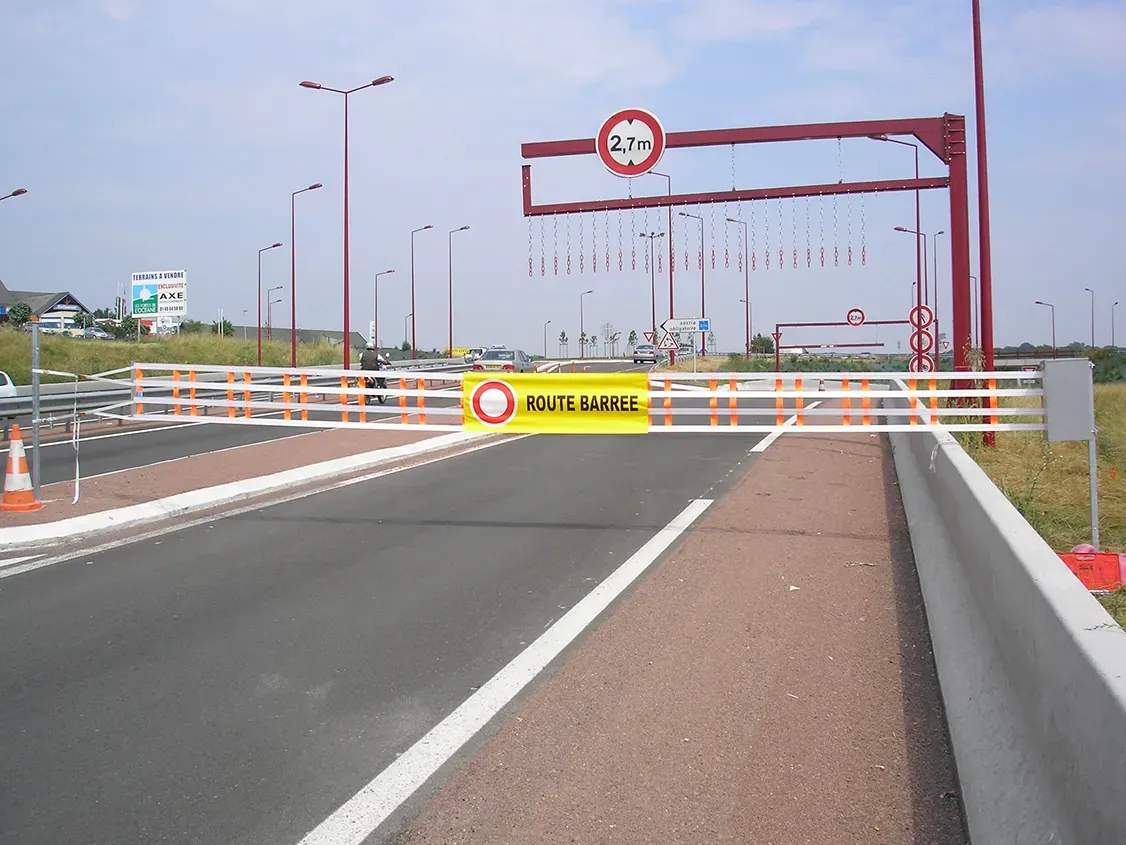 Barrière textile ROUTE BARRÉE fermant un accès de voie rapide sous un portique de gabarit